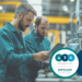 Experienced manufacturing workers using a tablet with digital work instructions and connected factory workflow data.